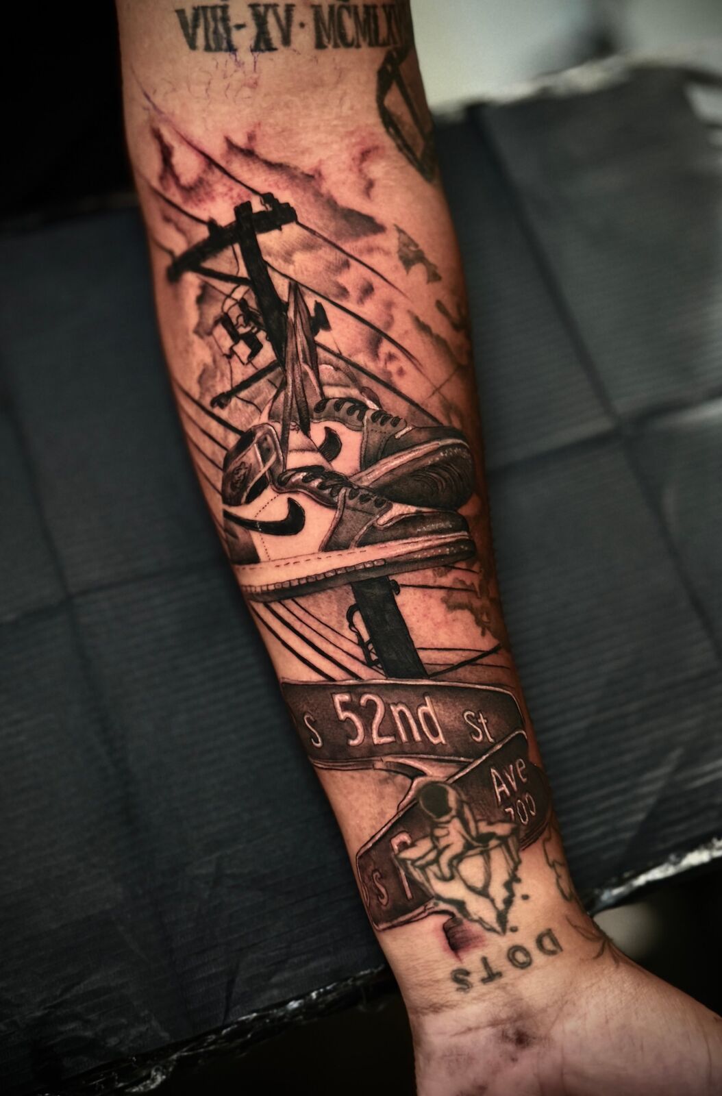 Forearm piece with sneakers hanging from a power line over street signs